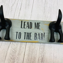 Load image into Gallery viewer, wooden plaque with two dog lead hooks and the text lead me to the bar