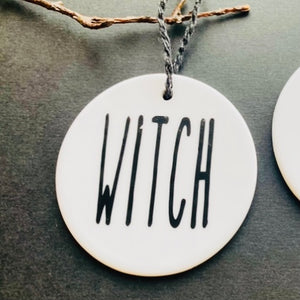 white bauble with black string and the word witch