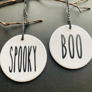 white bauble with black string and the word spooky or boo